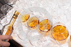 Closeup of the hand of the waiter pouring champagne into glasses