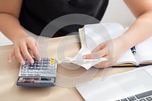 Closeup hand woman calculating expenses household and writing notebook on desk, girl checking bill and stress and note