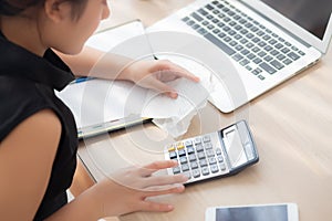 Closeup hand woman calculating expenses household and writing notebook on desk, girl checking bill and stress and note