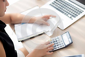 Closeup hand woman calculating expenses household and writing notebook on desk