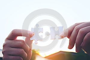 Closeup hand of woman connecting jigsaw puzzle with sunlight, symbol of association and connection