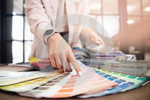 Closeup hand of woman decorator, interior and graphic designer, architect is choosing catalogue colors ral for web