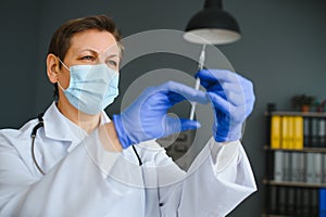 Closeup hand of woman doctor or scientist in doctor's uniform wearing face mask protective in lab holding medicine