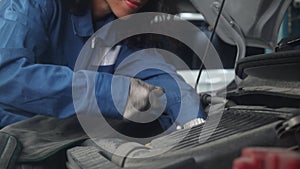 Closeup hand of woman is mechanic repairing engine of car in the garage.