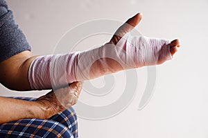 Closeup hand wrapped with bandage on sprain wrist, injury arm treatment.