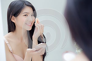 Closeup hand of young asian woman holding product cosmetic applying cream in jar