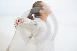 Closeup on hand of young woman in sweater on lonely beach