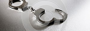 Closeup of handcuffs on obscure stainless steel background for prison