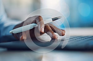 Closeup hands of african man holding a pen and working on a laptop. African american business man using computer while