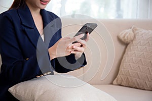 Closeup hands of asian businesswoman using smartphone to social media online sitting on sofa.