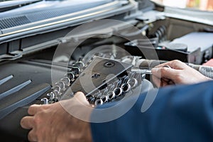 Closeup hands of auto mechanic holding wrench fixing car engine