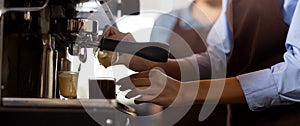 Closeup hands of barista preparing making coffee cappuccino or latte while pouring milk in coffee cup in cafe, close-up young