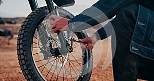 Closeup, hands or bike to repair, tire or tools as travel safety, mechanic or service off road. Technician, motorcycle