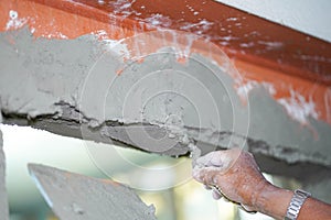 Closeup hands of builder holding mortar pan and plastering walls with cement in construction site