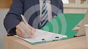 Closeup hands of businessman signing document about agreement and contract important of legal in folder in the office.