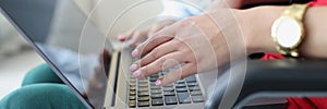 Closeup of hands of busy young woman and freelancer student friend sitting in chair with laptop