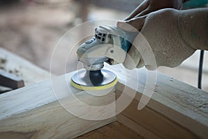 Closeup hands of carpenter using a power tool wood sander in workshop