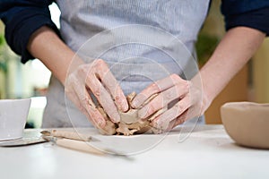Closeup hands of ceramic artist wedging clay in art studio