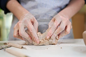 Closeup hands of ceramic artist wedging clay in art studio photo