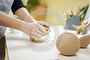 Closeup hands of ceramic artist wedging clay on a desk in art studio photo
