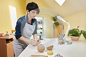 Closeup hands of ceramic artist wedging clay on a desk in art studio photo