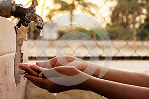 Closeup of hands, child drinking water directly from corporation tap water in India