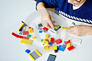 Closeup of hands of child playing with lots of colorful plastic blocks. Kid having fun with building and creating robot