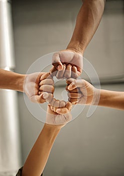 Closeup of hands of colleagues with fists joined. Zoom into hands of coworkers fists joined from below. Group of