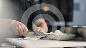 Closeup hands of cook staff cutting onion on table board using knife. 4k Dragon RED camera