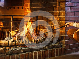 Closeup hands with fire iron poker at fireplace.