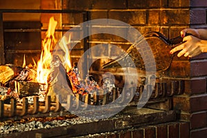 Closeup hands fireplace making fire with bellows.