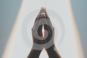 closeup of hands folded in prayer in a ray of light