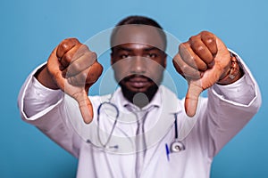 Closeup of hands giving thumbs down of dissapointed african american doctor