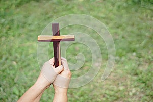 Closeup hands hold wooden cross, crucifix outdoor.
