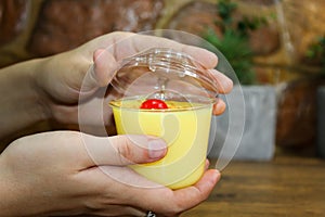 Closeup of hands holding a Guatemalan Dessert "Manjar" in a transparent plastic cup photo