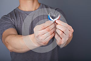 Closeup of hands holding small inconspicuous hearing aids in heart shape