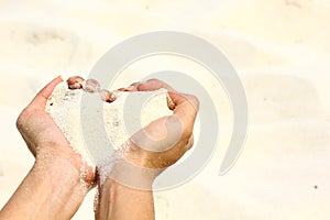 Closeup hands holding white sand heart shape