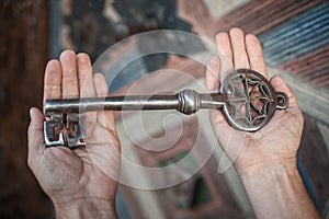 Closeup of hands holds old large huge massive metal key