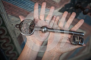 Closeup of hands holds old large huge massive metal key