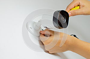Closeup of hands installing a home security camera on a white wall