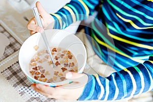 Closeup of hands of kid boy eating homemade cereals for breakfast or lunch