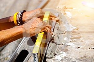 Closeup hands of laborer holding a building level working at construction site