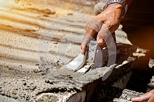 Closeup hands of laborer holding wood trowel working at construction site