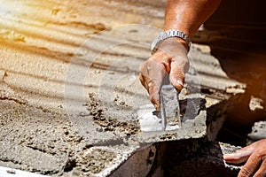 Closeup hands of laborer holding wood trowel working at construction site