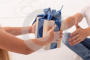 Closeup of hands of little girl and her father who hold gift box in hands. Selective focus