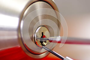 Closeup hands of locksmith using metal pick tools to open locked door photo