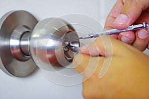 Closeup hands of locksmith using metal pick tools to open locked door