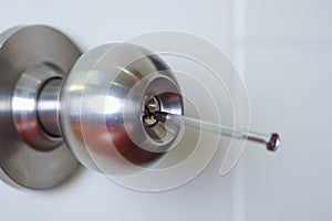 Closeup hands of locksmith using metal pick tools to open locked door