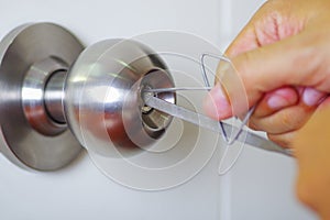 Closeup hands of locksmith using metal pick tools to open locked door