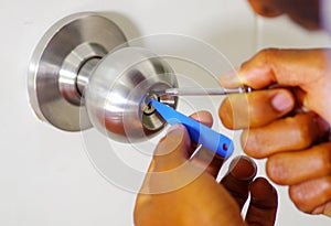 Closeup hands of locksmith using pick tools to open locked door